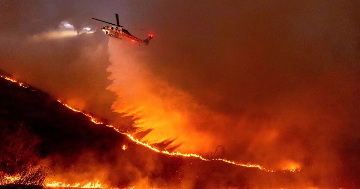 Helicopter dropping water on wildfire at night