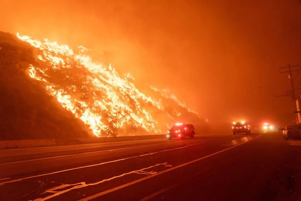 Cars driving on a road with hillside on fire